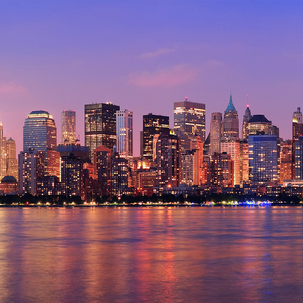 New York City Manhattan downtown skyline at dusk with skyscrapers illuminated over Hudson River panorama